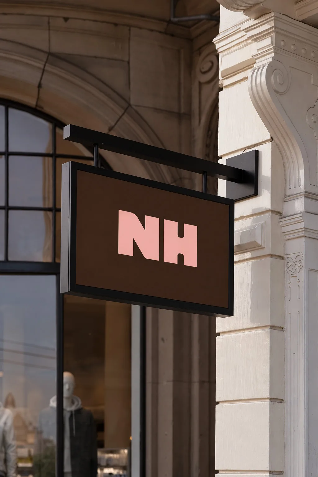 The new NH sign in pink on chocolate, hung from a stone façade